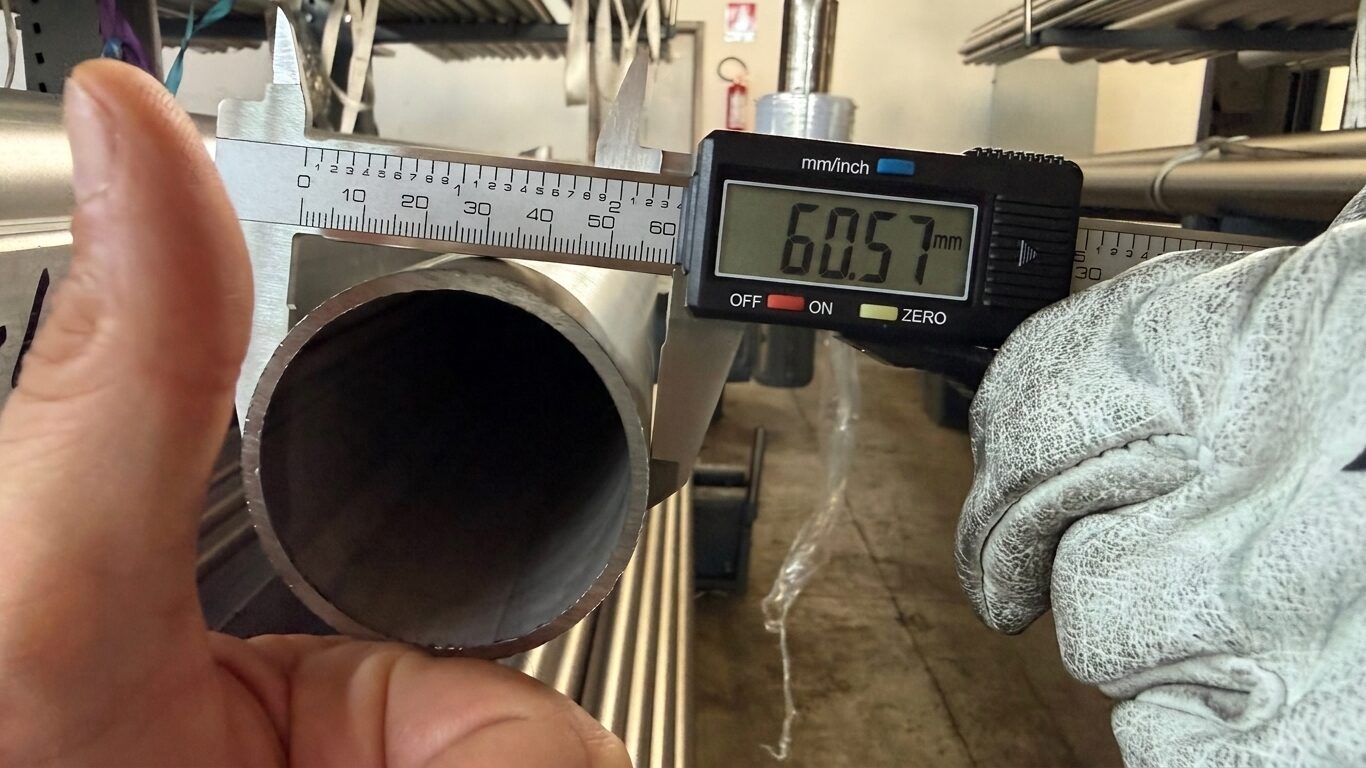 Controllo qualità in magazzino: misurazione con calibro digitale del diametro di un tubo in acciaio inossidabile.